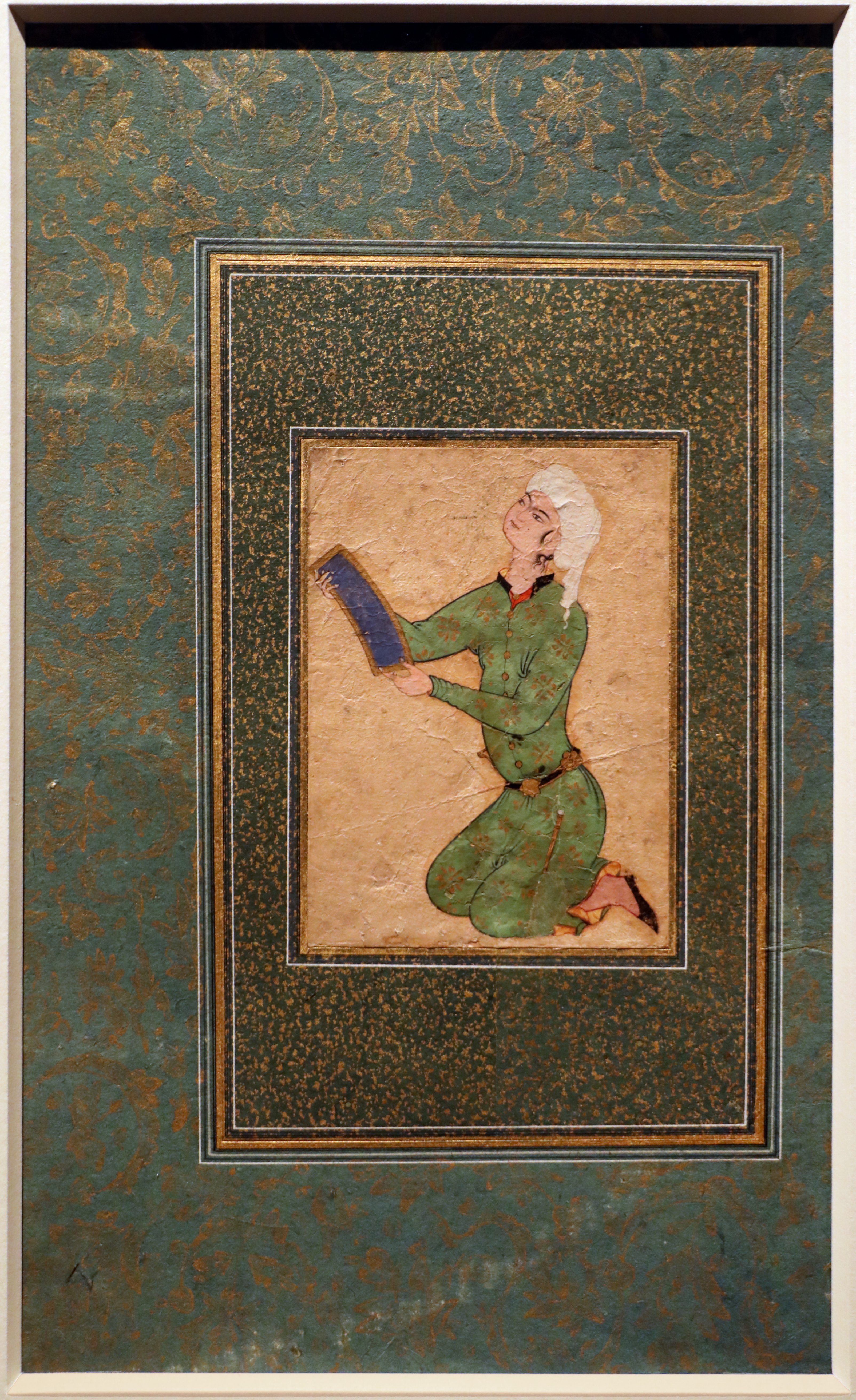 Iran, giovane in abito di broccato che tiene una raccolta di poesie safina, mashhad 1550-1600 ca